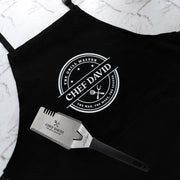 Personalised BBQ hamper with custom apron and engraved stainless steel BBQ tool featuring The Grill Master design.