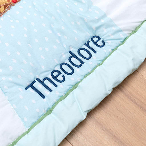 Close-up of custom name embroidery on safari-themed cotton baby blanket and play mat.