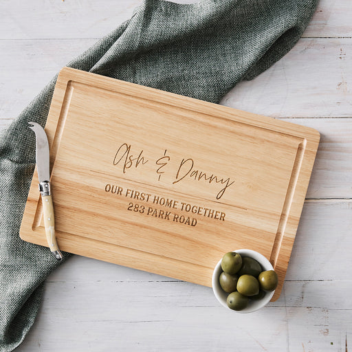 Personalised rectangular wooden cheese board with engraved housewarming design.