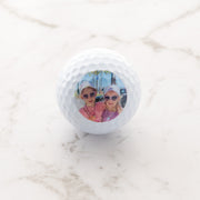 Set of three personalised golf balls with custom photo, presented in a black gift box.