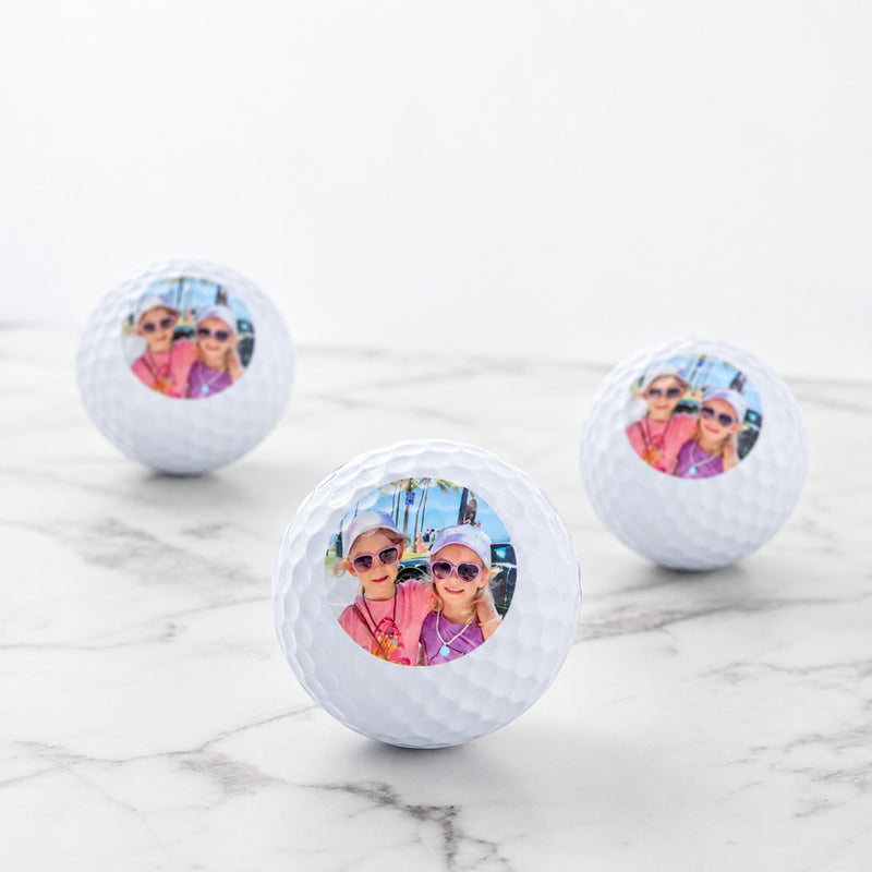 Set of three personalised golf balls with custom photo, presented in a black gift box.