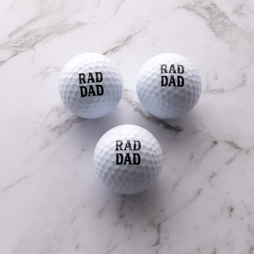Three premium golf balls printed with "Rad Dad" and presented in a black gift box for golf-loving dads.