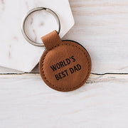 Tan leatherette round keyring engraved with "World's Best Dad" featuring a silver keyring and stitched edge detail, perfect for Father's Day.
